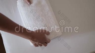 <strong>双</strong>手特写，把一叠新鲜的白色浴巾放在床单上。 客房服务员清洁酒<strong>店</strong>客房